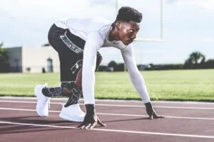 man staat op atletiekbaan en is klaar om te rennen